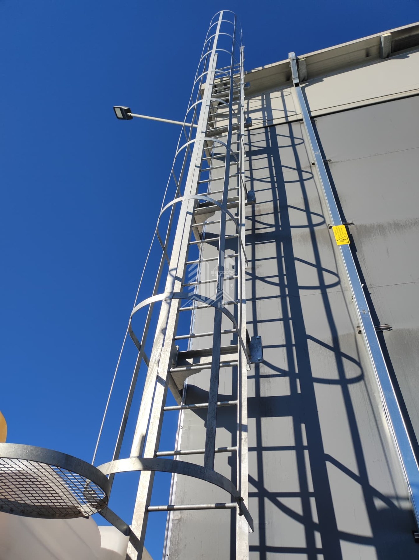 Scala di accesso alla copertura con gabbia di protezione e linea di ancoraggio verticale