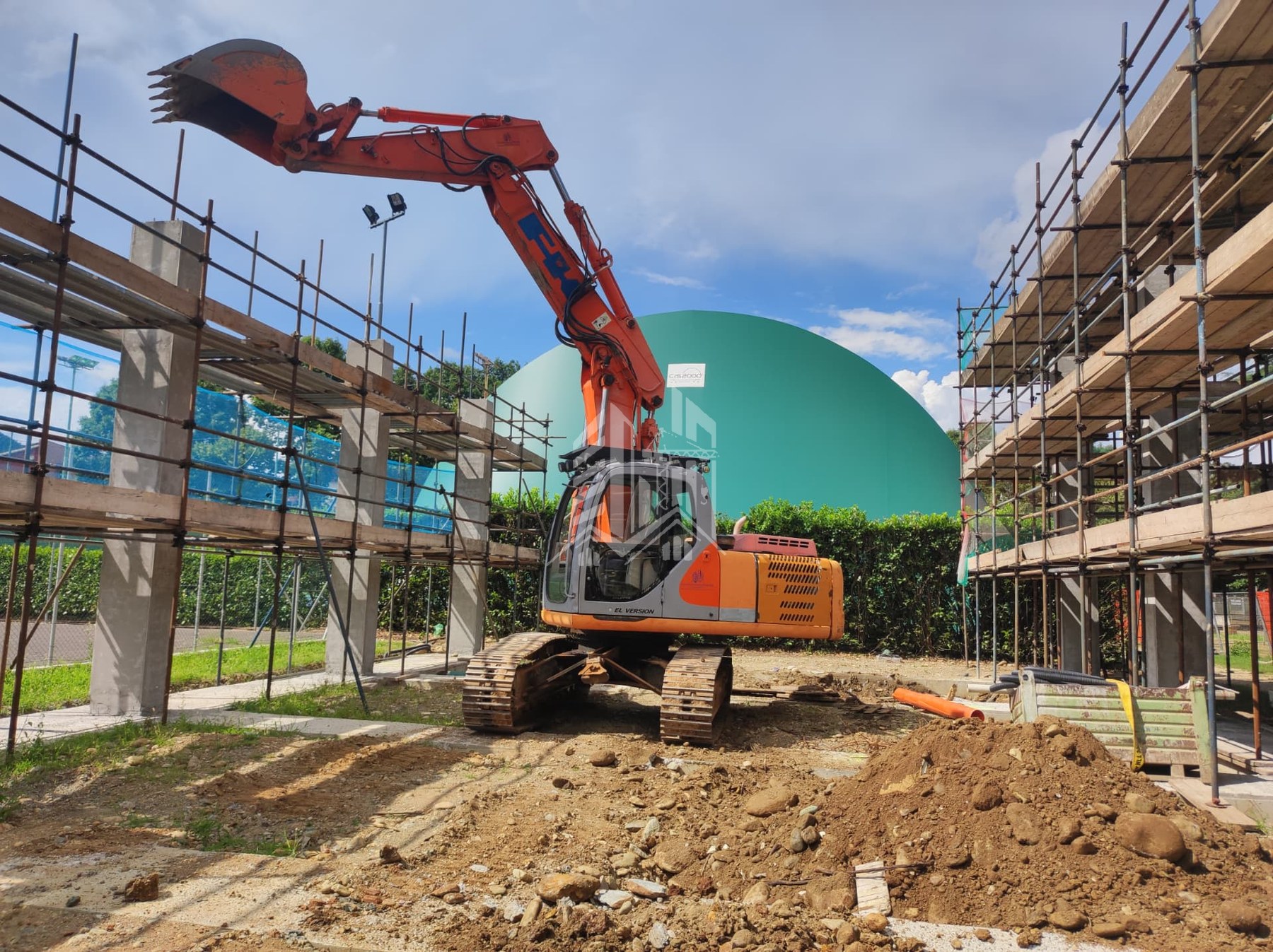 Escavatore cingolato al lavoro nel cantiere con ponteggi