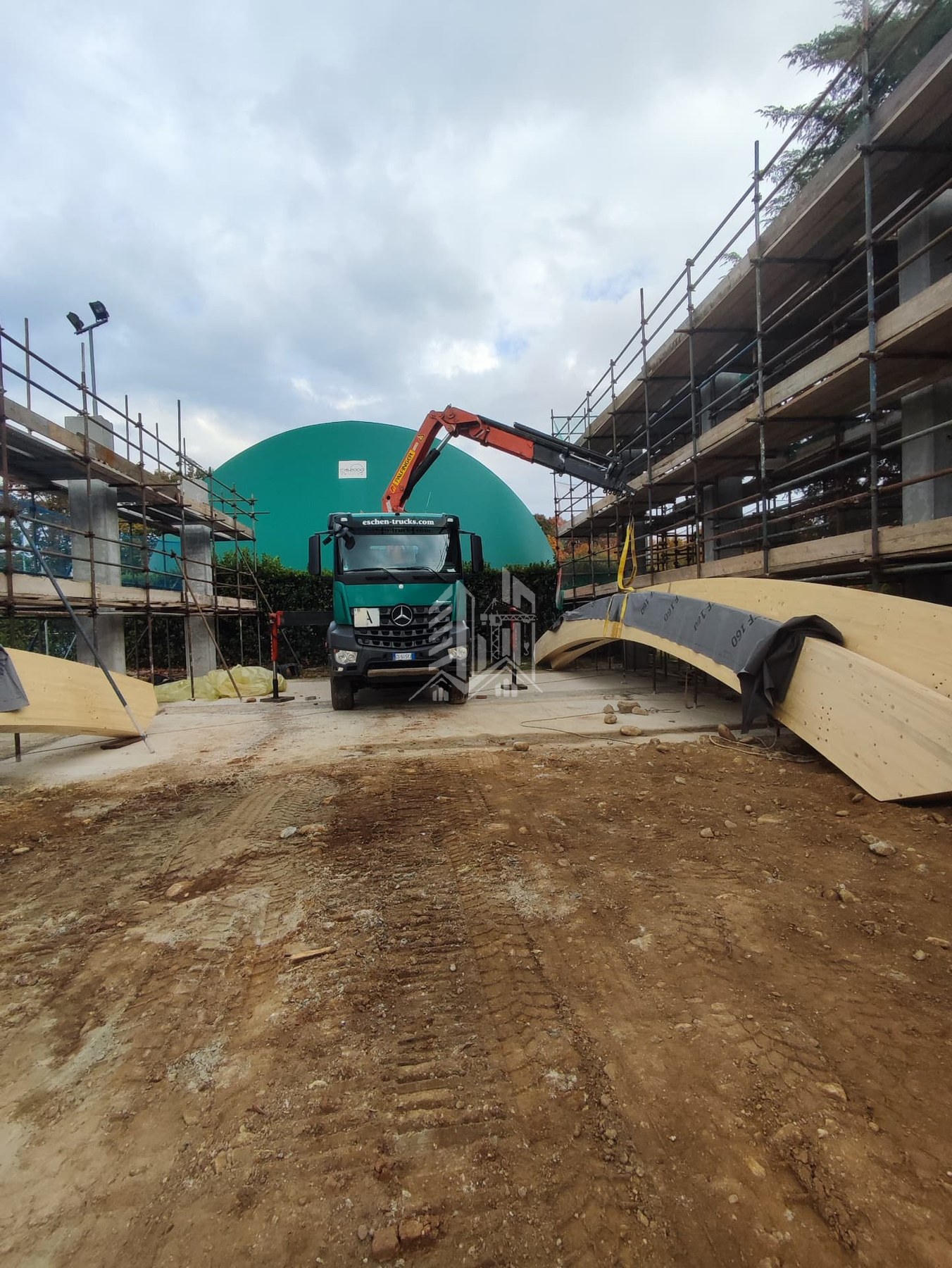 Autocarro con gru e travi curve in legno lamellare in cantiere